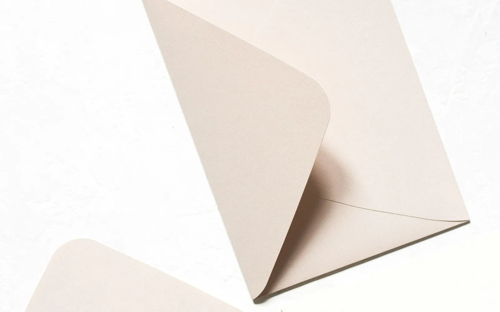 Pale pink paper envelope with an open flap on a white surface