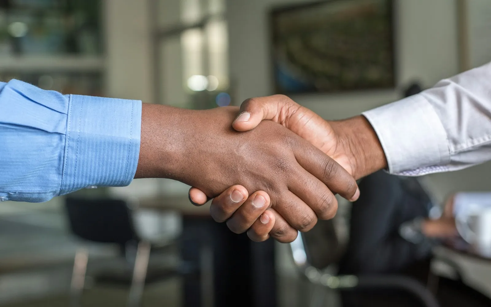 Close-up of two people in shirt sleeves shaking hands in an office