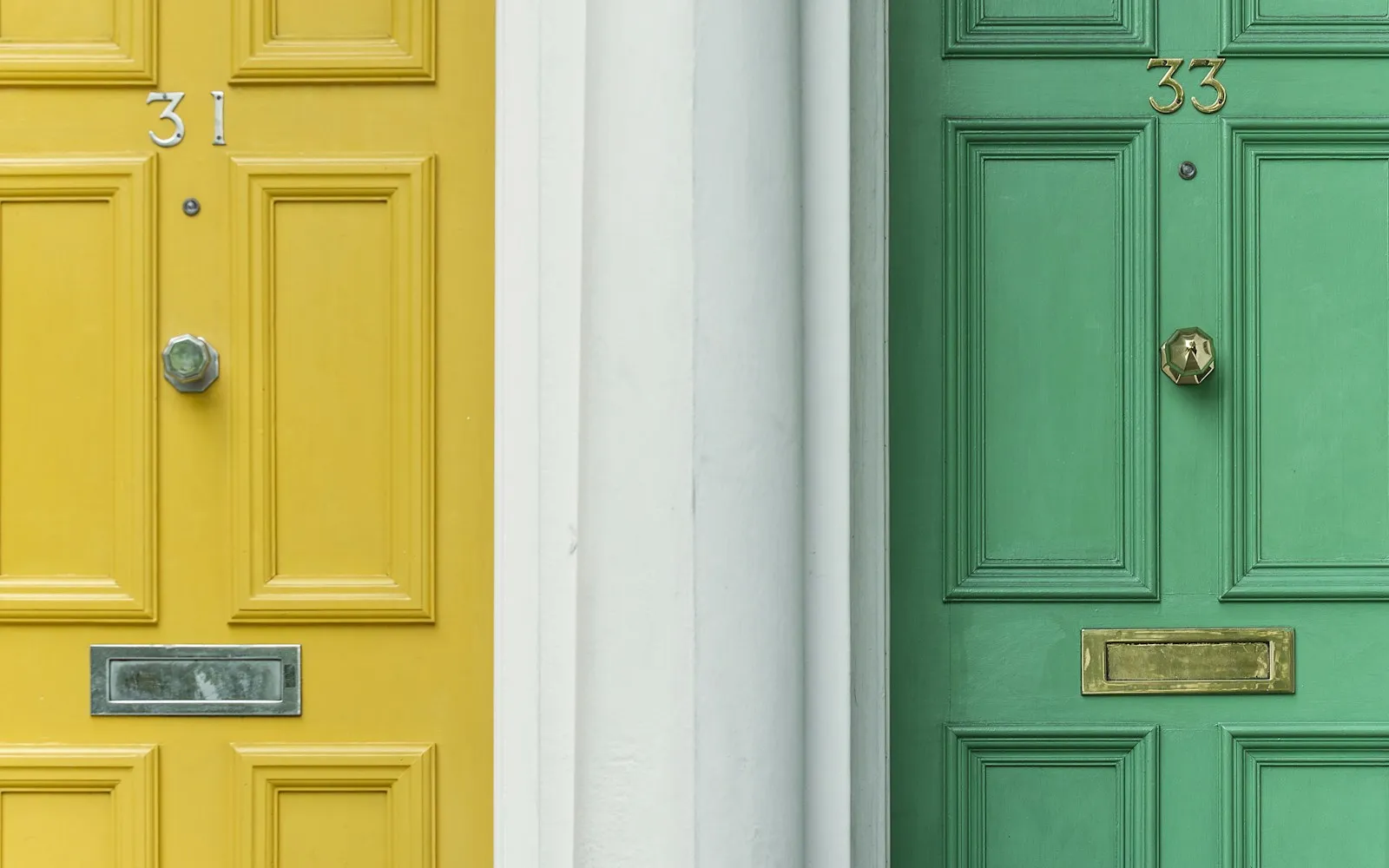 Side-by-side yellow door number 31 and green door number 33 with matching knockers and letter slots