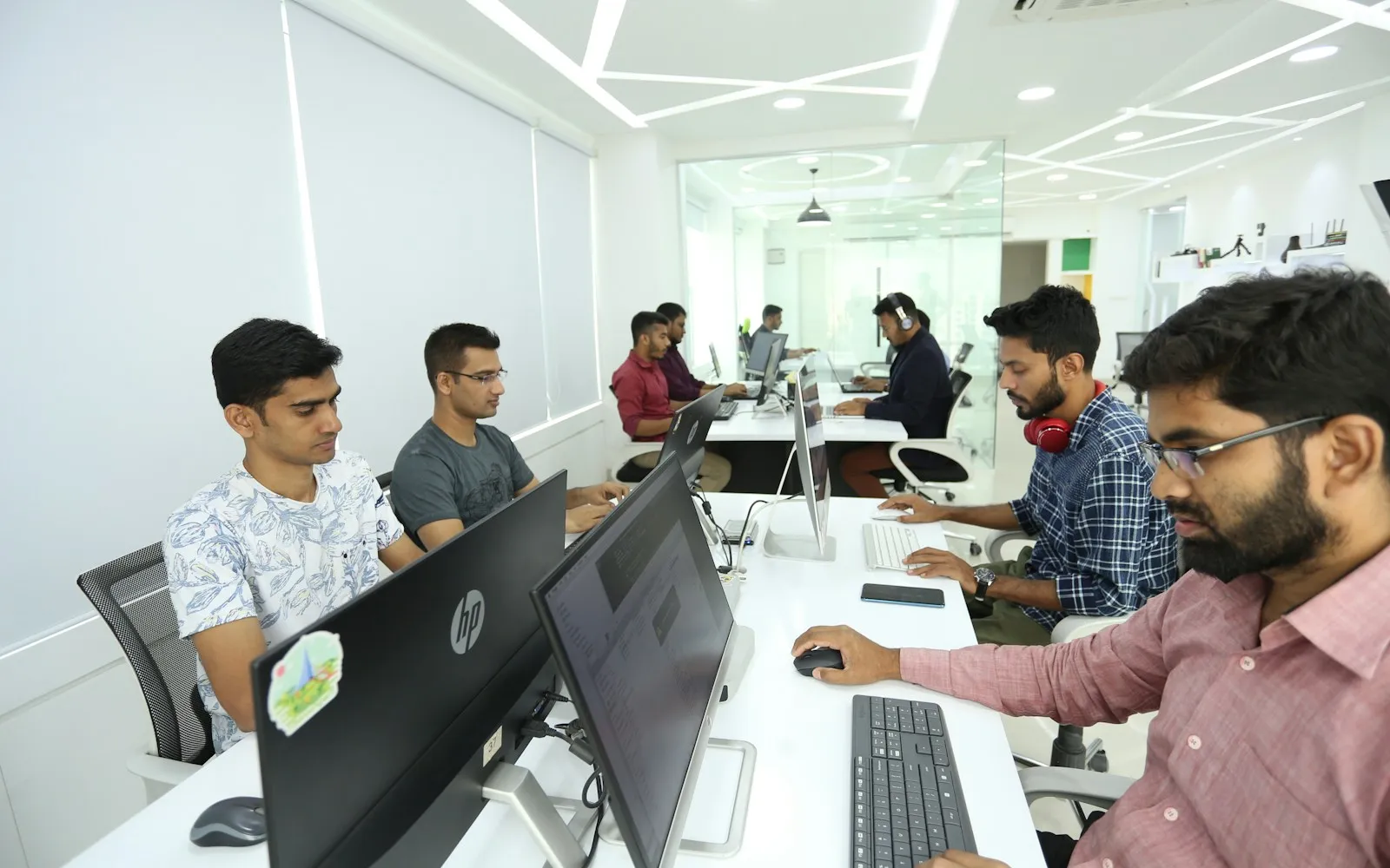 Developers working at rows of computer monitors in a bright open-plan office