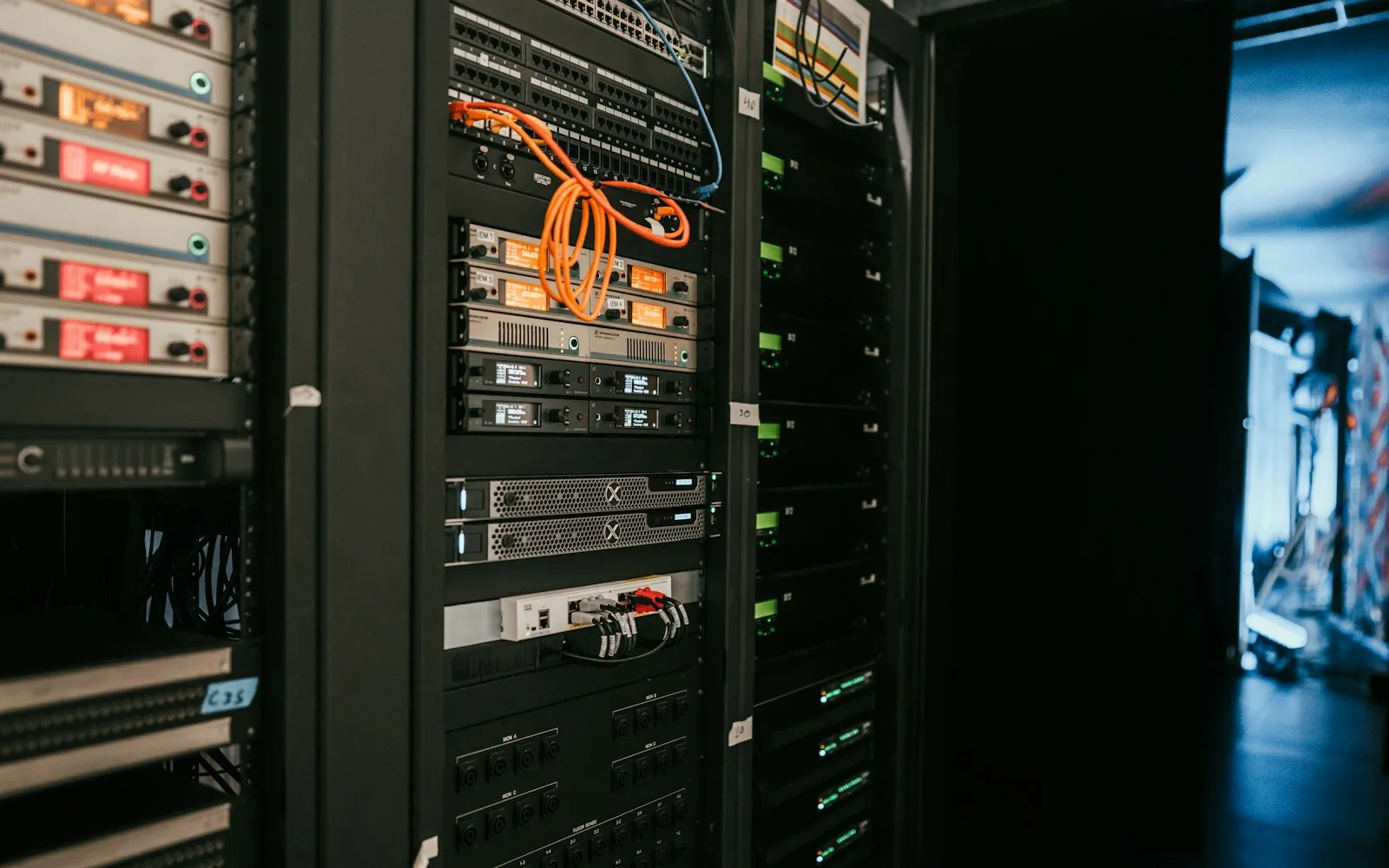 Server racks with network switches, patch cables and rack-mounted equipment in a dark room