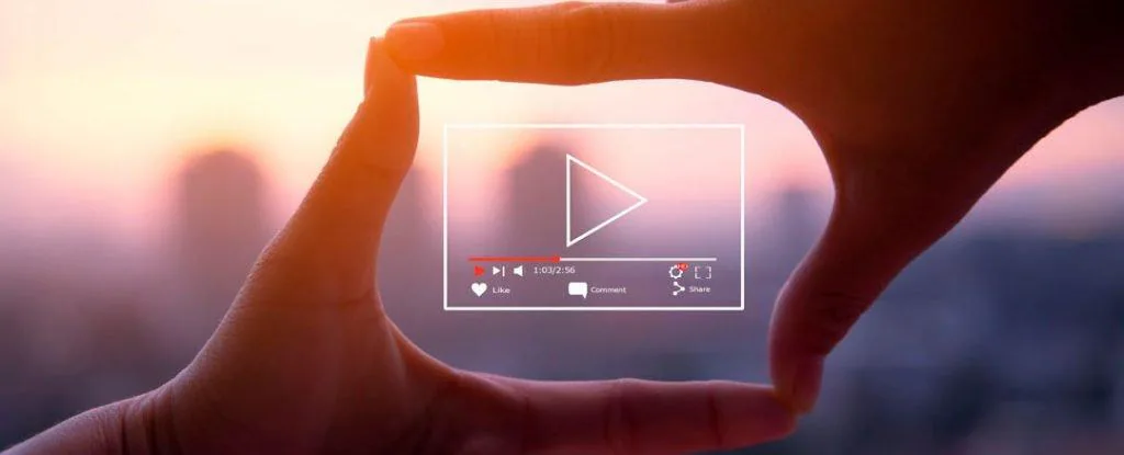 Two hands forming a frame around a video play button against a sunset
