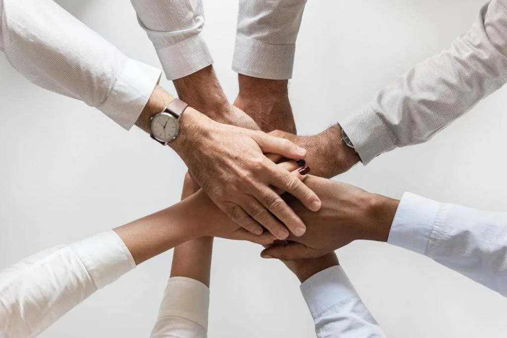 Team members stacking their hands together in a show of teamwork