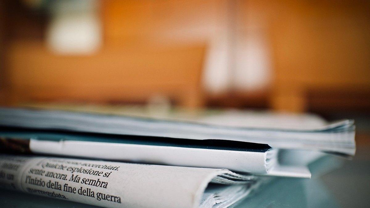 Editor highlighting concise sentences on a printed article beside a laptop to make content quotable