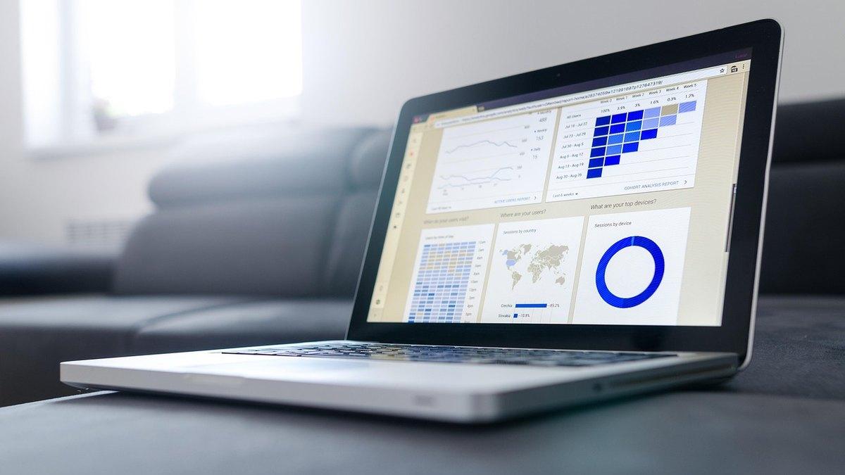 Two colleagues review a pricing spreadsheet and charts on a laptop at a office desk
